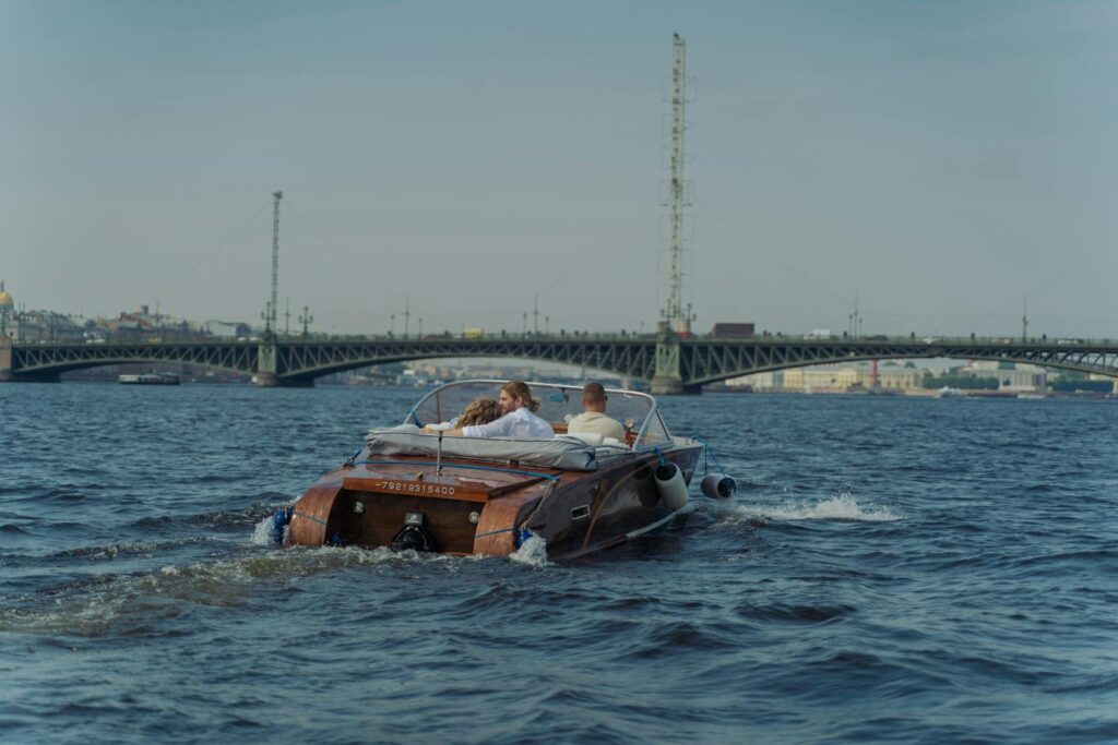 Couple enjoying a speedboat ride on a scenic river with a bridge view.
